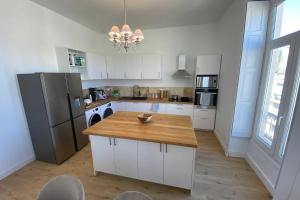 a kitchen with white cabinets and a wooden counter top at Sunny luxury flat in the city centre in Montpellier