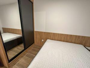 Dormitorio pequeño con cama y espejo en Hrast Apartman Šestosjed Trnovo, en Jahorina
