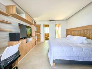 a bedroom with a large bed and a flat screen tv at Suite, Eco Hotel Laguna Beach in Tolú