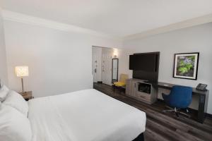 um quarto com uma cama, uma secretária e uma televisão em La Quinta by Wyndham Miami Airport West em Miami