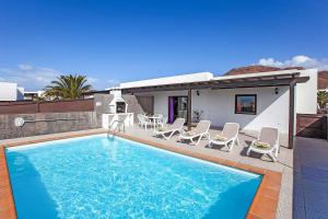 a swimming pool with chairs and a house at Villas Rodríguez in Playa Blanca