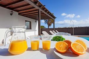two glasses of orange juice and three oranges on a table at Villas Rodríguez in Playa Blanca
