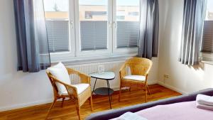 グレーミッツにあるGrüntal-Residenz Haus I App. 5の椅子2脚、テーブル、窓が備わる客室です。