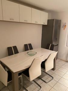 eine Küche mit einem Tisch mit Stühlen und einem Kühlschrank in der Unterkunft Claude et Carole in Obenheim