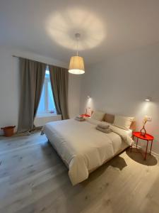 a white bedroom with a large bed and a lamp at Les amies in Blankenberge