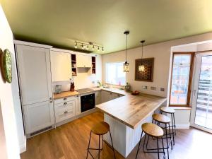 a kitchen with white cabinets and a wooden counter top at Beautiful House in London - Abbey Wood in Abbey Wood