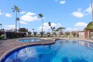 a swimming pool in a resort with palm trees at Kihei's Seaside Siesta: Ocean View Lanai & Pool in Kihei