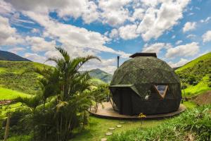uma casa de cúpula num campo com montanhas ao fundo em Freedome Domos e Chalés em São Francisco Xavier