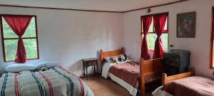 a bedroom with two beds and two windows at Cabaña Brisas del Lago in Tolhuin