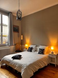 - une chambre avec un grand lit blanc et deux lampes dans l'établissement Le manoir de la Cane, à Montfort-sur-Meu