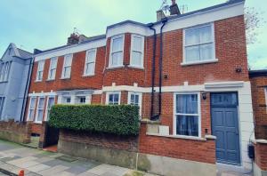 una casa de ladrillo con una puerta azul en una calle en Luxury Fulham 3 bedroom Garden House en Londres