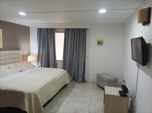 Conforta Rentals & Spa في بوبايان: غرفه فندقيه سرير وتلفزيون