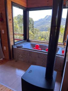 a bath tub in a room with a large window at Chalés incríveis com banheira de hidromassagem e vista encantadora in Urubici