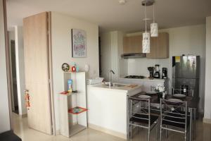 eine kleine Küche mit einem Tisch und einem Kühlschrank in der Unterkunft Condo La Aldea 2 Hab. Vista Única. Muy Tranquilo in Ricaurte