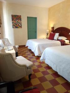 a hotel room with two beds and a chair at Hotel Palacio Chico 1948 in Antigua Guatemala