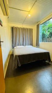 ein Schlafzimmer mit einem Bett in einem Zimmer mit einem Fenster in der Unterkunft Casa Container na Praia do Rosa / Ibiraquera in Imbituba