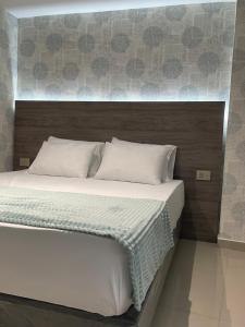 Una cama con sábanas blancas y almohadas en un dormitorio en Luxury liv Gran limonar, en Cali