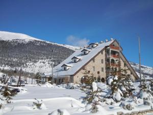 um grande edifício na neve com uma montanha em Villa Anemar em Blidinje