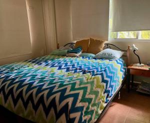 ein Bett mit farbenfroher Bettdecke in einem Schlafzimmer in der Unterkunft Relaxing family Beach House with Pool in Río Hato