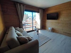 uma sala de estar com um sofá e uma televisão de ecrã plano em Appartement montagne LE FLOCON em Saint-Michel-de-Chaillol