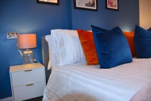 um quarto com uma cama com almofadas coloridas e um candeeiro em Bard's Nest Scholars Cottage, Central Stratford, 5 mins walk to RSC em Stratford-upon-Avon