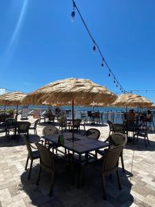 a table with chairs and umbrellas on the beach at Waterfront Resort Condo with Balcony Close to Beaches Free Bikes in Dunedin