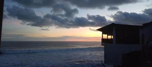 um pôr-do-sol numa praia com um edifício e o oceano em Sunset View - Mini Loft em La Libertad