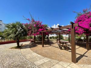 a pavilion with a picnic table and pink flowers at Taste Tavira (by Annick) fully equipped apartment, tastefully decorated, perfect location and free parkingric center of the city of Tavira. in Tavira