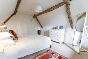 a bedroom with a white bed and a dresser at The Holford Arms in Tetbury