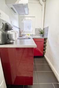 a small kitchen with red cabinets and a sink at Le 15 - Appartement pour 4 personnes - Disneyland Paris in Esbly