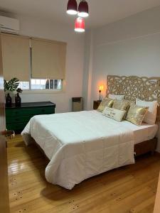 1 dormitorio con 1 cama blanca grande con almohadas en Experiencia Aguirre a dos cuadras del subte B. Corazon de outlets, comercios y bares gastronomicos. en Buenos Aires