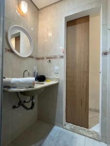 baño con lavabo, espejo y puerta en Apartamento quadra da praia, en Río de Janeiro