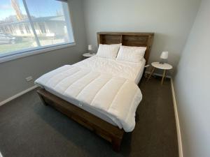 a bed in a room with two tables and a window at Allendale in Berridale