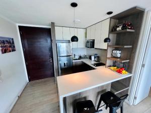 una cocina con encimera y algunas sillas. en Apartamento cerca Mall Alto las Condes en Santiago