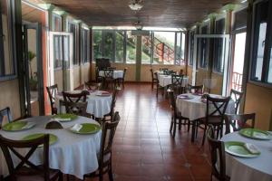a restaurant with white tables and chairs and windows at Ribiera del Lago Peten Itza in Flores