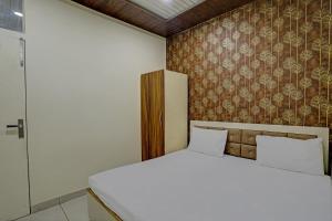 a bedroom with a white bed and a wall at Super OYO Hotel Krishna Guest House & PG in Ludhiana