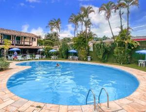 a pool at a resort with a person swimming at VELINN Pousada dos Marinheiros in Ilhabela