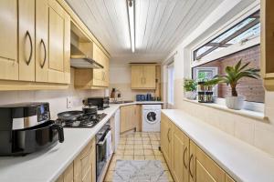 a large kitchen with wooden cabinets and a window at Beautiful 2 bedroom house Free Parking, Aylesbury, Adrenham st in Buckinghamshire