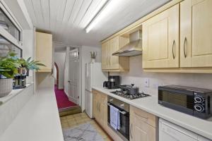 a kitchen with wooden cabinets and a stove top oven at Beautiful 2 bedroom house Free Parking, Aylesbury, Adrenham st in Buckinghamshire