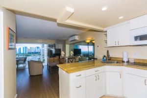 a kitchen with white cabinets and a living room at Ilikai Tower 1137 Yacht Harbor View 1BR in Honolulu