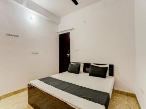 a bedroom with a bed with white walls at OYO Varusiya Guest House in Bhauli