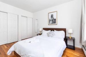 a white bedroom with a large bed and two lamps at 2Bed Bliss by Central Park North in New York