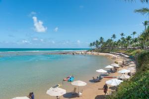 a beach with umbrellas and people on the beach at Nannai Residence Muro Alto Porto de Galinhas por Brevelar in Porto De Galinhas