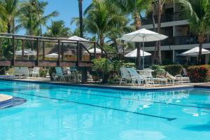 a pool at a resort with chairs and umbrellas at Nannai Residence Muro Alto Porto de Galinhas por Brevelar in Porto De Galinhas