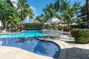 a swimming pool with chairs and tables and palm trees at Nannai Residence Muro Alto Porto de Galinhas por Brevelar in Porto De Galinhas +152 photos