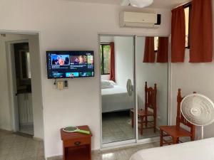 een kamer met een televisie aan de muur met een spiegel bij Cita del Sol City Apartments in Cabarete