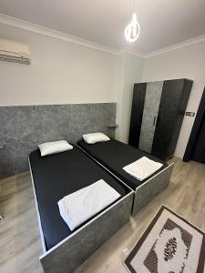 Schlafzimmer mit einem schwarzen Bett und weißen Kissen in der Unterkunft Meydan Suite Apartments in Trabzon
