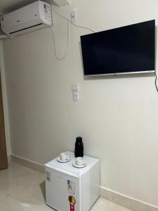 a room with a tv on a white wall at Residencial santiago in Porto Seguro