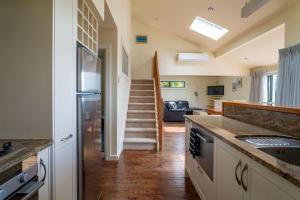 a kitchen with a refrigerator and a living room at Koru Lodge in Raglan