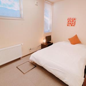 1 dormitorio con cama blanca y ventana en Minowa airbnb en Yubari